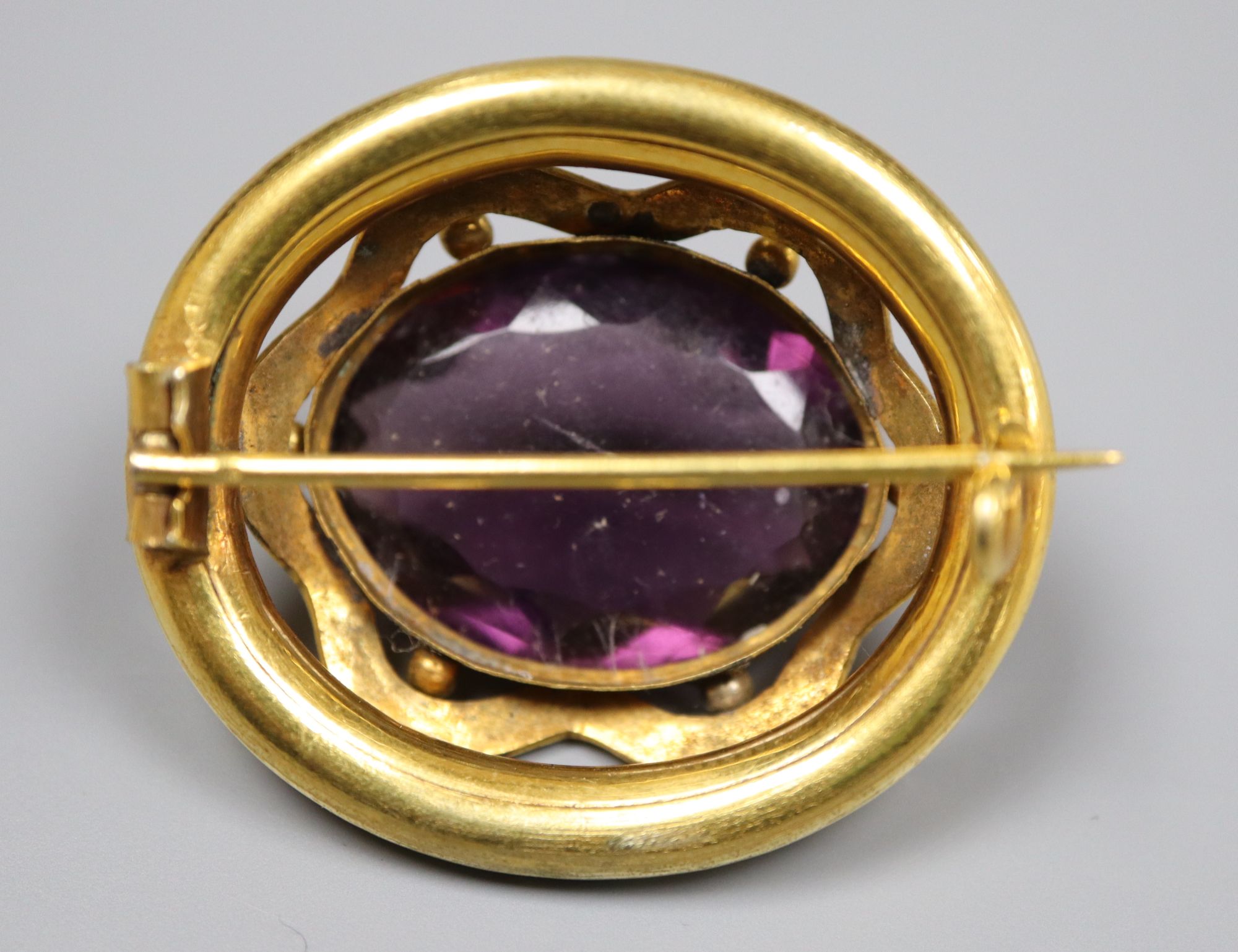 A Victorian pinchbeck and facetted amethyst paste set oval brooch, 37mm.